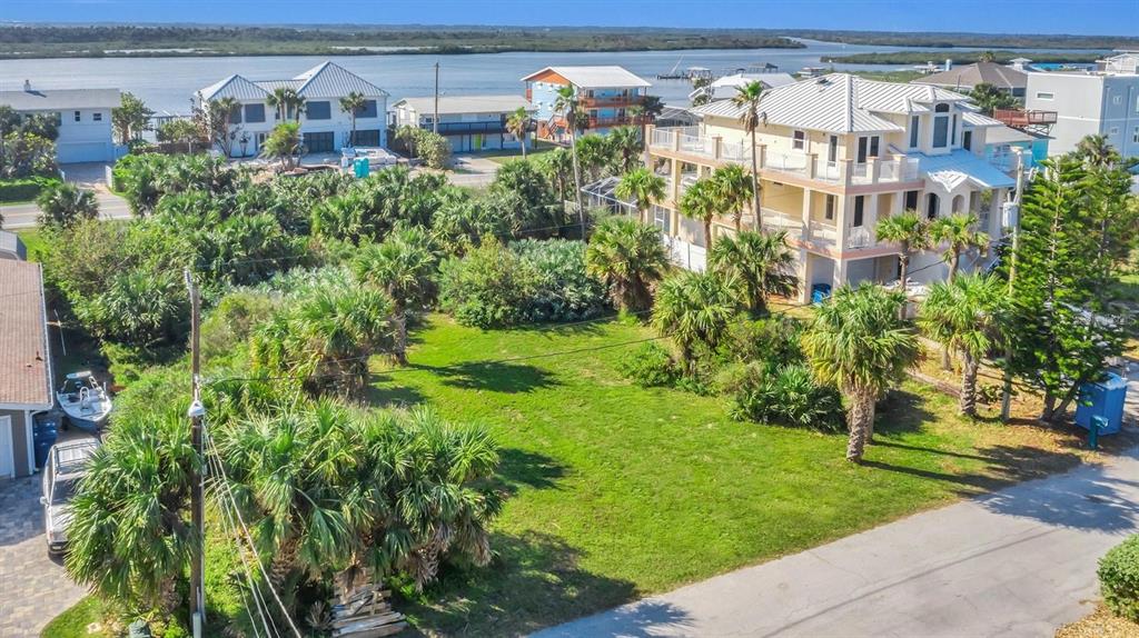 An aerial view shows a vacant grassy lot surrounded by palm trees and coastal houses — 0 S ATLANTIC AVE, NEW SMYRNA BEACH, FL