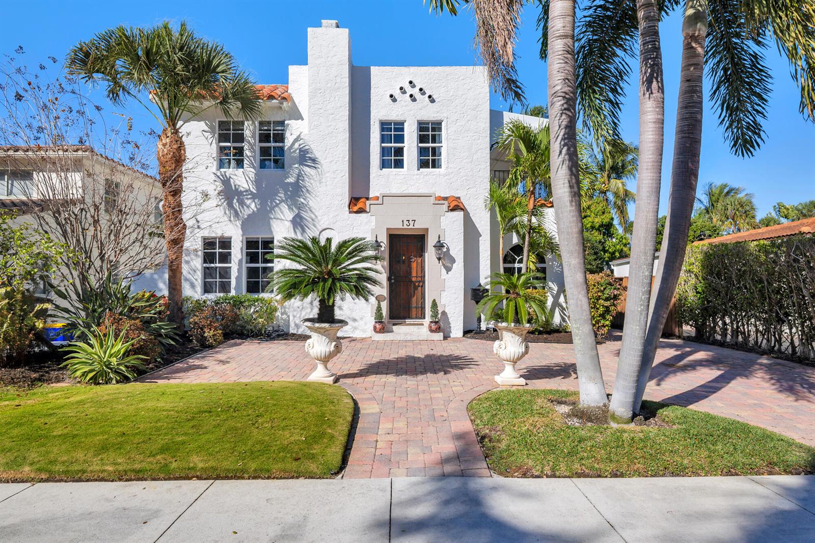 A two-story white stucco house features a tiled roof, arched entryway, and a brick driveway — 137 Edgewood Drive, West Palm Beach FL 33405, WEST PALM BEACH, FL
