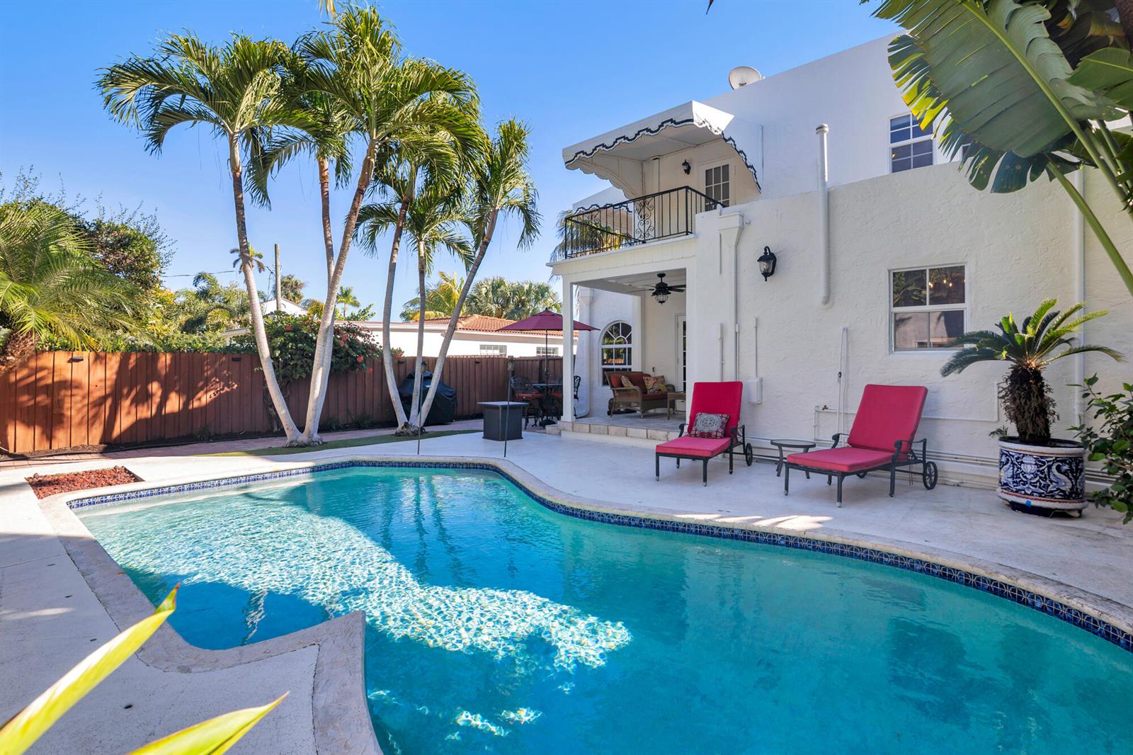 A swimming pool sits in front of a white two-story house with a balcony — 137 Edgewood Drive, West Palm Beach FL 33405, WEST PALM BEACH, FL