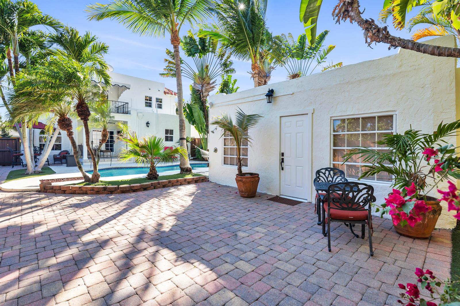 A paved patio features a small table with chairs, potted plants, and a swimming pool — 137 Edgewood Drive, West Palm Beach FL 33405, WEST PALM BEACH, FL