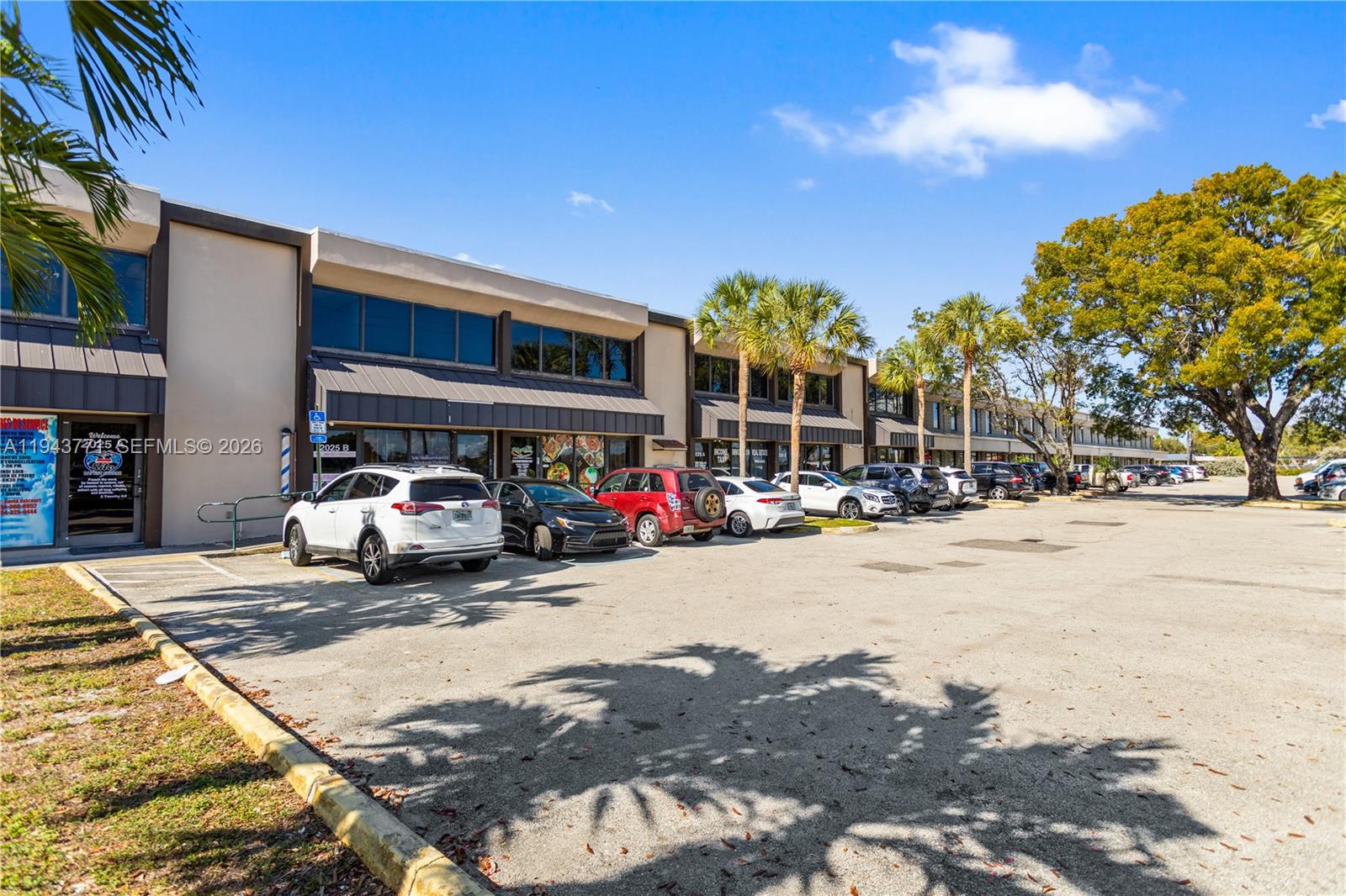 A row of commercial storefronts with a parking lot in front under a blue sky — 2025 N Dixie Hwy, Pompano Beach FL 33060, POMPANO BEACH, FL