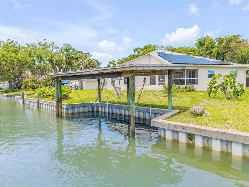 A waterfront house features a wooden boat dock and solar panels on the roof — 192 AZALEA ROAD, EDGEWATER, FL