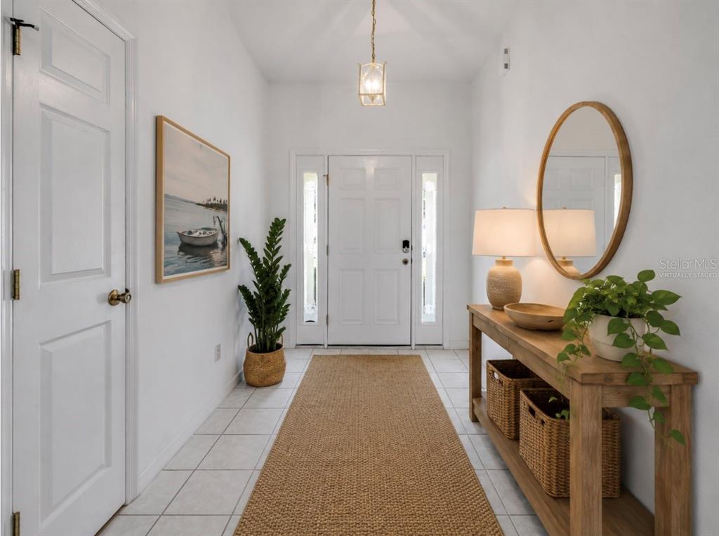 A bright entryway features white walls, tile flooring, a wooden console table, and a front door — 192 AZALEA ROAD, EDGEWATER, FL