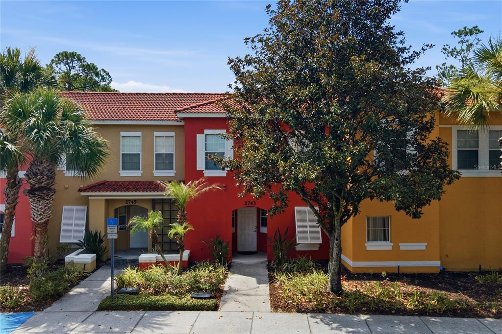 A multi-story townhouse complex features red and yellow stucco facades with tiled roofs — 2743 SUN KEY PLACE, KISSIMMEE, FL