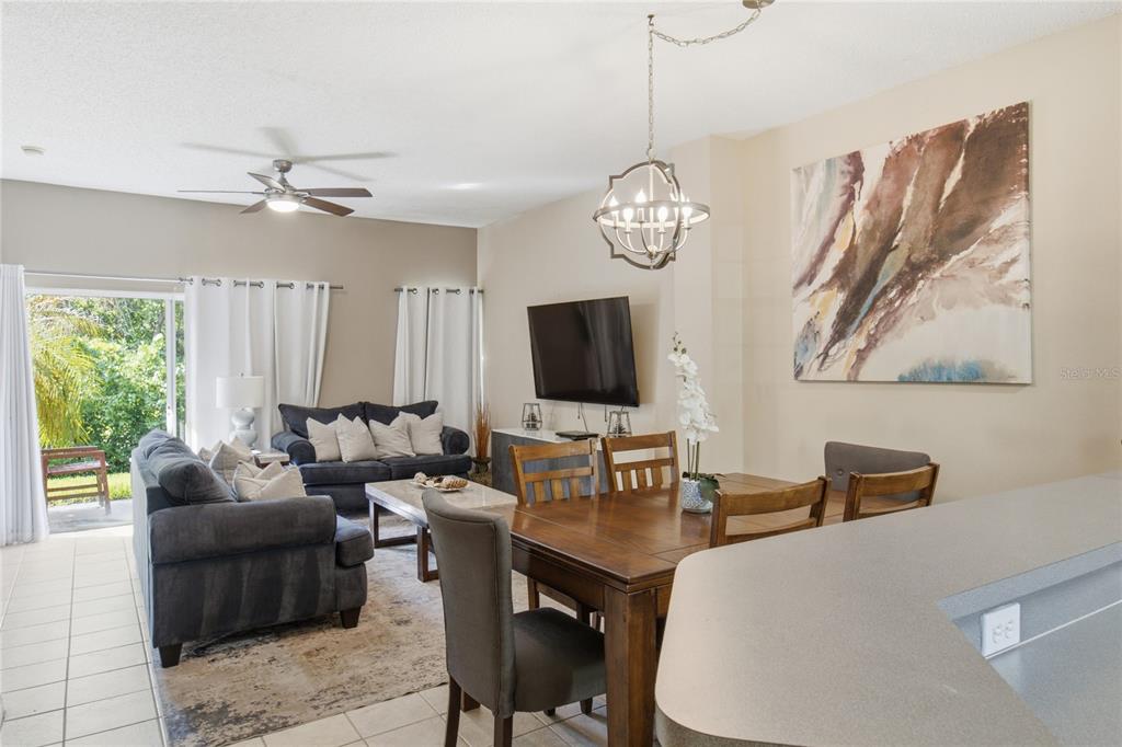 An open-concept living and dining area features tile flooring, a ceiling fan, and sliding doors — 2743 SUN KEY PLACE, KISSIMMEE, FL