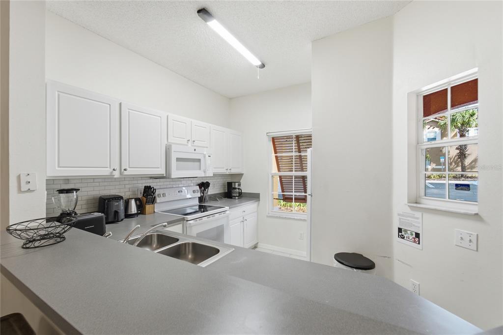 A kitchen with white cabinets, gray countertops, a double sink, and two windows — 2743 SUN KEY PLACE, KISSIMMEE, FL