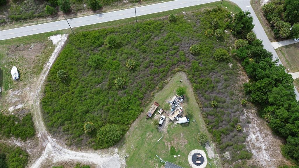 An aerial view shows a large, undeveloped grassy lot with scattered trees and parked vehicles — 2065 CHAPLIN DRIVE, PUNTA GORDA, FL