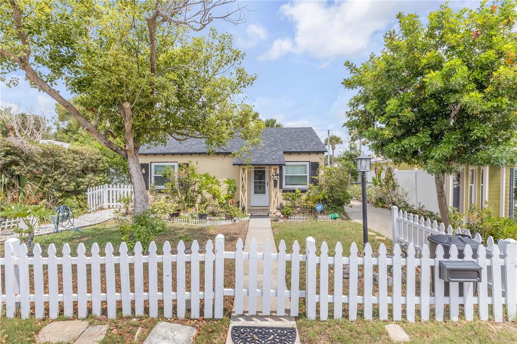 A small, single-story house with a white picket fence and a paved walkway — 204 CONDICT DRIVE, NEW SMYRNA BEACH, FL