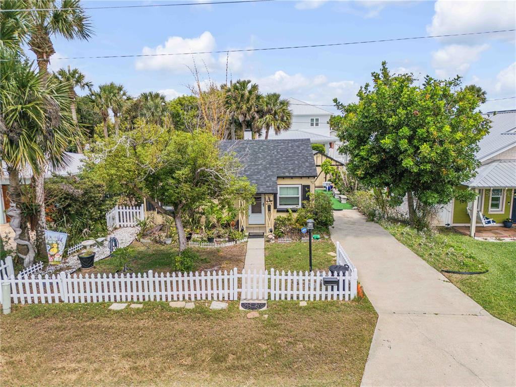 An exterior view of a small, single-story house with a white picket fence and driveway — 204 CONDICT DRIVE, NEW SMYRNA BEACH, FL