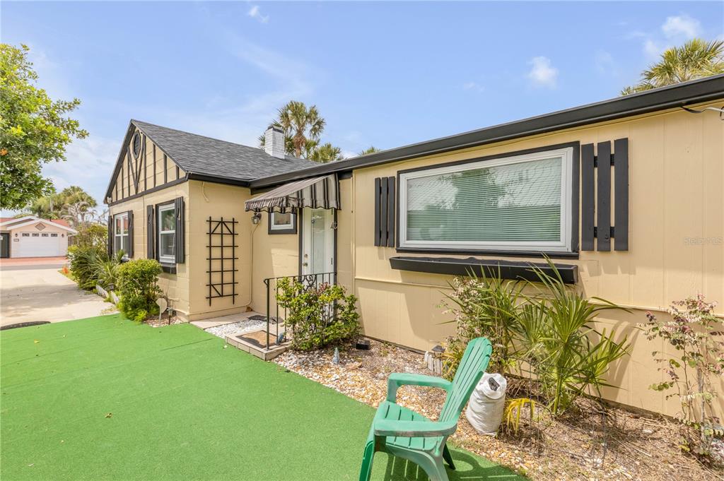 A single-story house with yellow siding, black shutters, and a green artificial turf front yard — 204 CONDICT DRIVE, NEW SMYRNA BEACH, FL