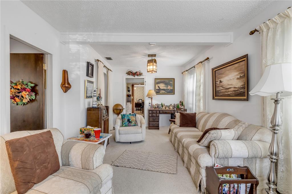 A living room features beige striped sofas, a desk, and a central ceiling light fixture — 204 CONDICT DRIVE, NEW SMYRNA BEACH, FL