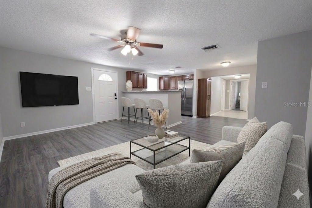 A living room with gray flooring, a sectional sofa, and an open kitchen with bar seating — 307 W WOODLAWN AVENUE, TAMPA, FL