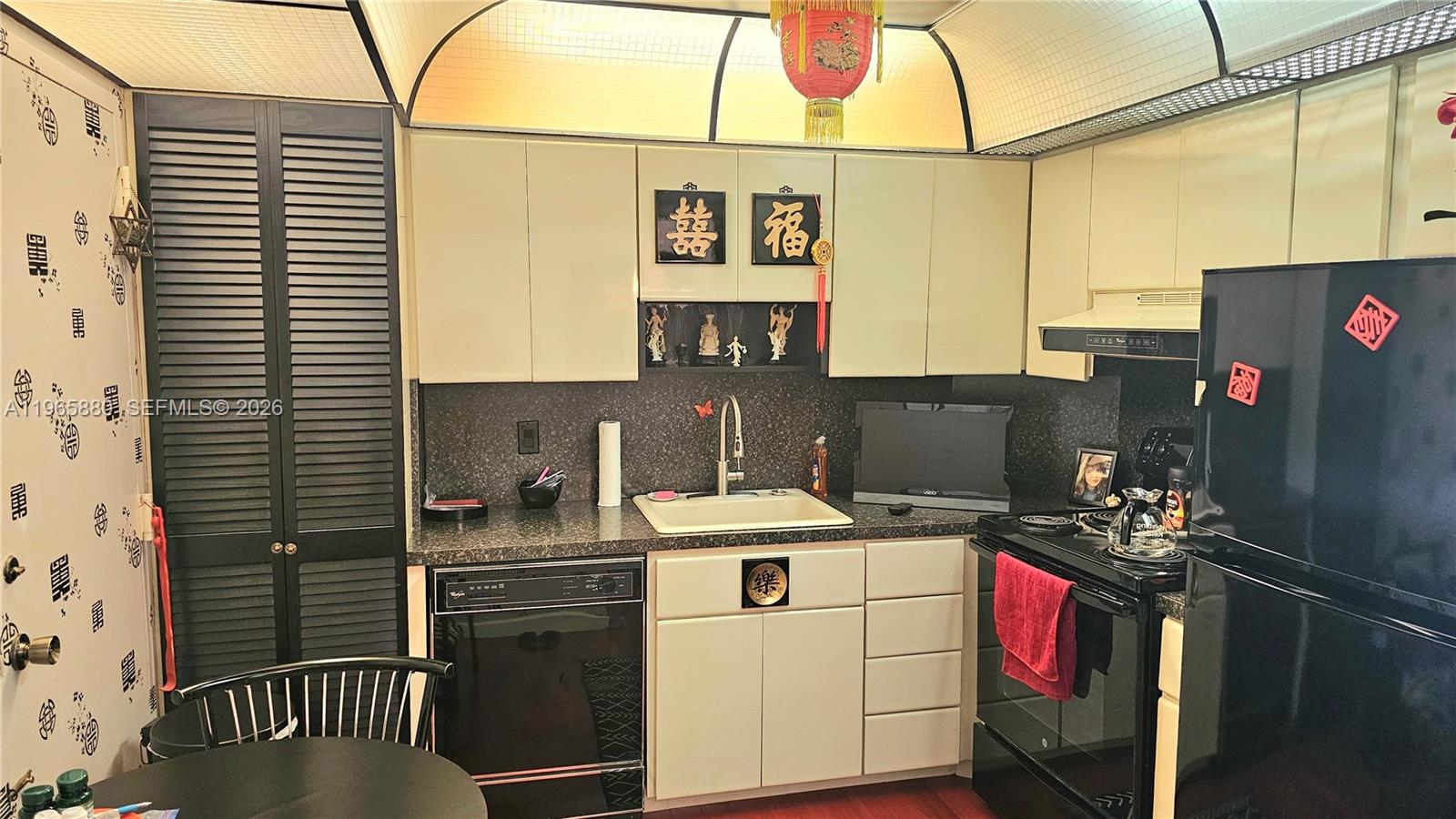 A kitchen features black appliances, light-colored cabinets, a dark countertop, and Asian-inspired wall decorations — 1985 S Ocean Dr # 10J, Hallandale Beach FL 33009, HALLANDALE BEACH, FL