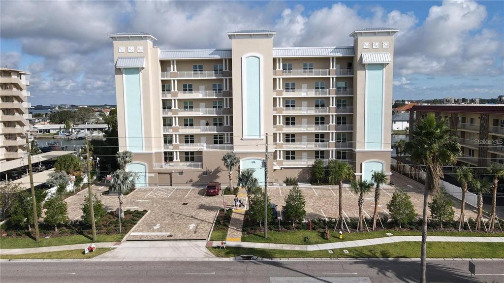 An exterior view of a multi-story apartment building with a paved parking lot in front — 125 ISLAND WAY UNIT 403, CLEARWATER, FL