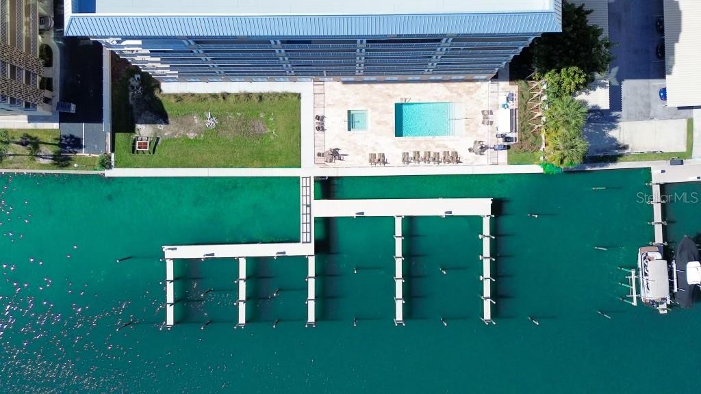 An aerial view shows a multi-story building with a pool deck and a boat dock — 125 ISLAND WAY UNIT 403, CLEARWATER, FL