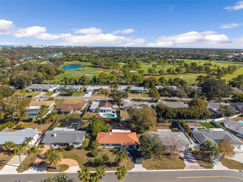 An aerial view shows a residential neighborhood with single-family homes and a nearby golf course — 610 PALM AVENUE, BELLEAIR, FL