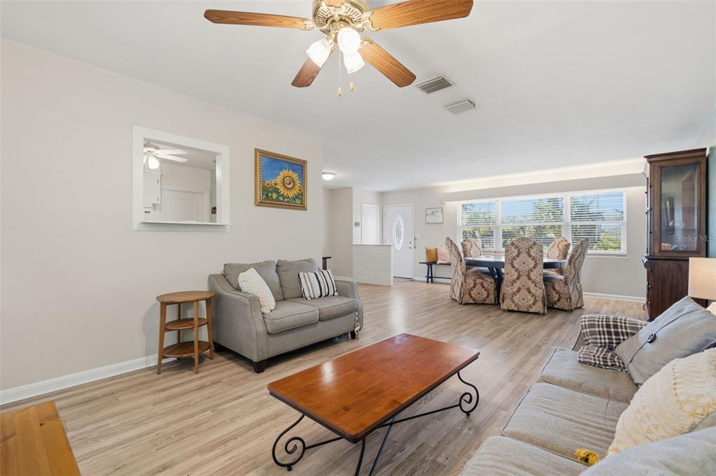 A living and dining area with light wood flooring, a ceiling fan, and neutral walls — 610 PALM AVENUE, BELLEAIR, FL