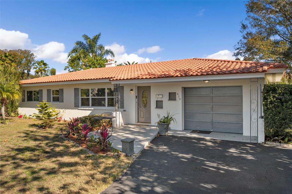 A single-story house with a terracotta tile roof, gray garage door, and front porch — 610 PALM AVENUE, BELLEAIR, FL