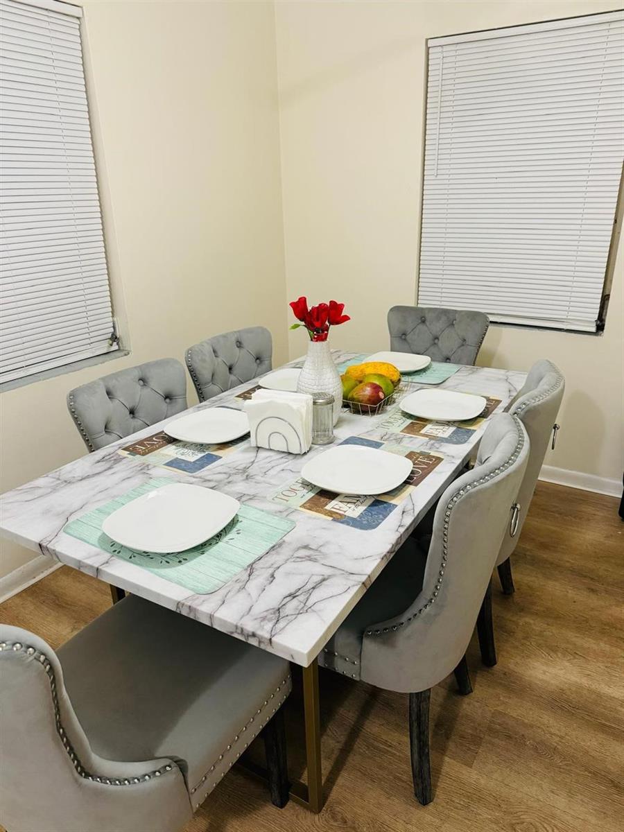 A dining room features a marble-top table with six tufted grey upholstered chairs — 958 W 4th Street, Riviera Beach FL 33404, RIVIERA BEACH, FL
