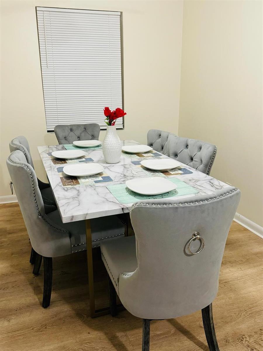 A dining room features a marble-top table with six grey tufted upholstered chairs — 958 W 4th Street, Riviera Beach FL 33404, RIVIERA BEACH, FL