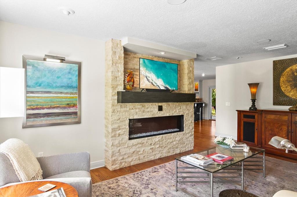 A living room features a stone fireplace with a mounted television and a glass coffee table — 1538 S ORANGE AVENUE, SARASOTA, FL