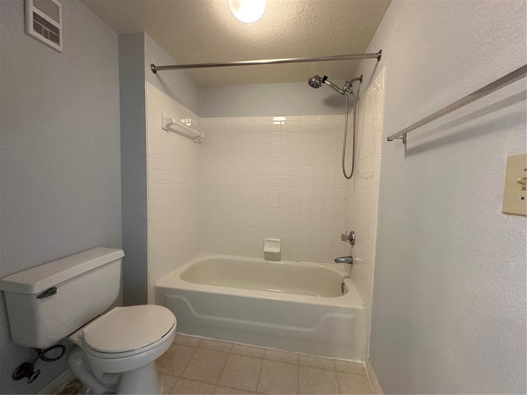 A bathroom features a white toilet, a tiled bathtub-shower combination, and a towel rack — 7270 WESTPOINTE BOULEVARD UNIT 916, ORLANDO, FL