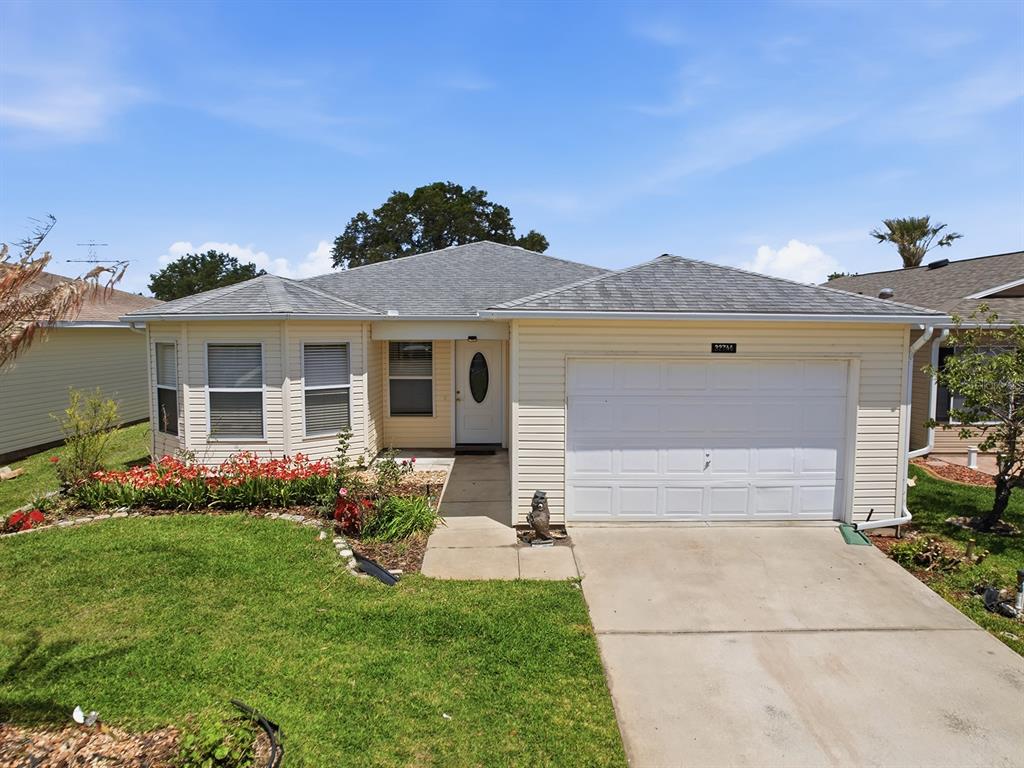 A single-story house with yellow siding, a white garage door, and a front lawn — 32744 WESTWOOD LOOP, LEESBURG, FL