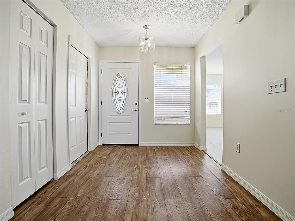 An entryway features wood-look flooring, a white front door with a glass insert, and a chandelier — 32744 WESTWOOD LOOP, LEESBURG, FL