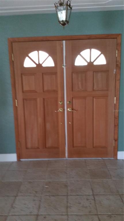 A pair of wooden double doors with arched glass panels set against a green wall — 1876 MID OCEAN CIRCLE, SARASOTA, FL