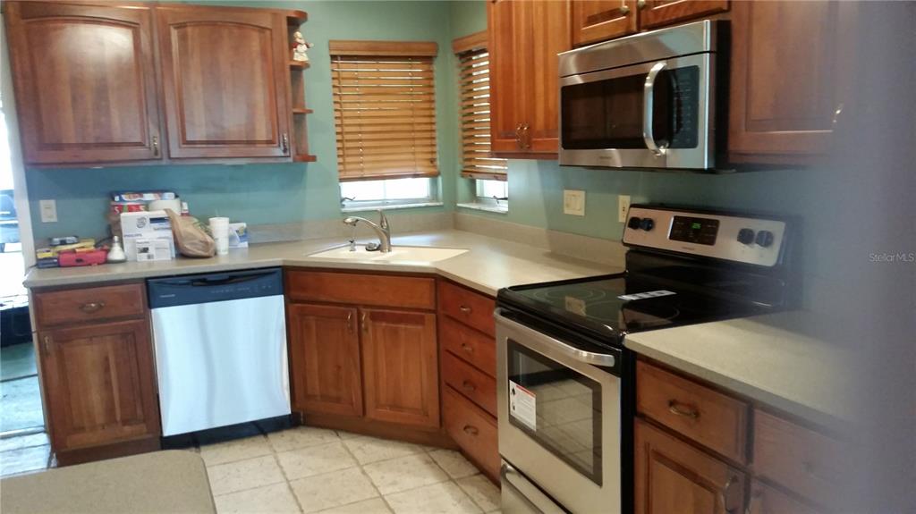 A kitchen features wood cabinets, stainless steel appliances, a corner sink, and light-colored countertops — 1876 MID OCEAN CIRCLE, SARASOTA, FL