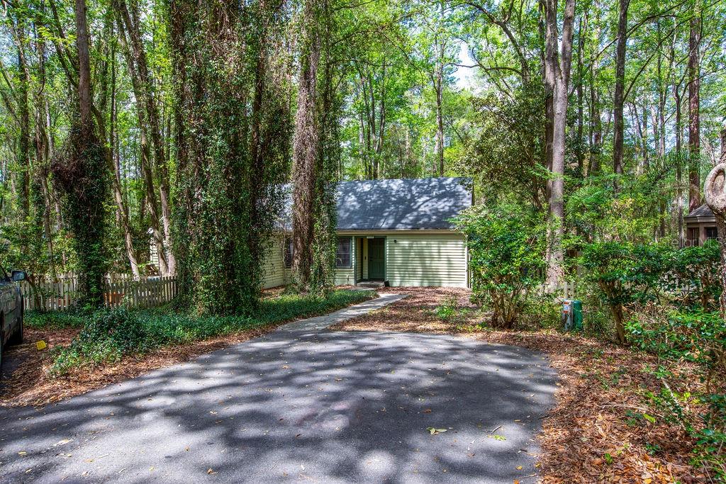 A light green house with a dark roof sits at the end of a driveway — 5208 SW 86TH TERRACE, GAINESVILLE, FL