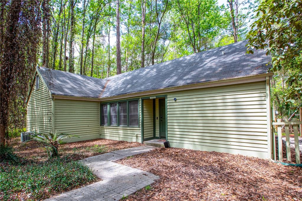 A light green, single-story house with horizontal siding sits in a wooded area — 5208 SW 86TH TERRACE, GAINESVILLE, FL