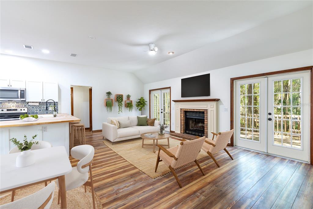 A bright living room features a fireplace, wood-look flooring, and glass doors to a deck — 5208 SW 86TH TERRACE, GAINESVILLE, FL