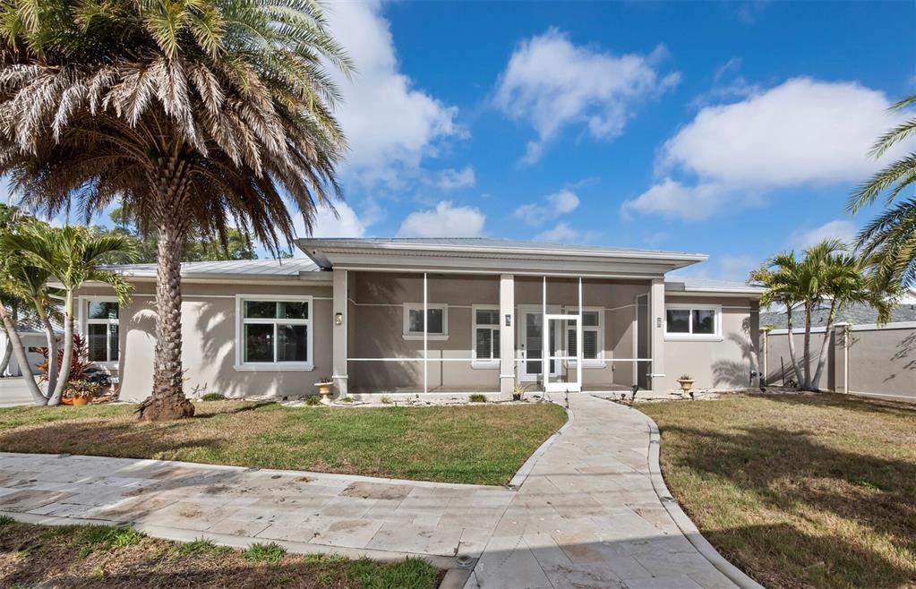 A single-story house with a screened-in porch, palm trees, and a stone walkway — 5618 BRITANNIA DRIVE, SARASOTA, FL