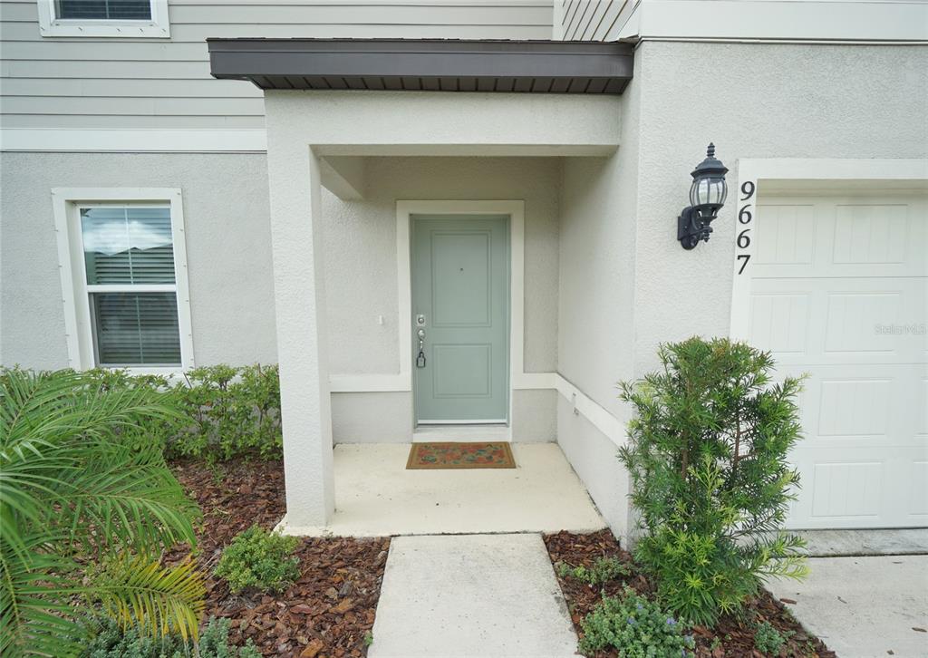 The exterior of a home features a light green front door and a garage — 9667 SUMMERS CAY CIRCLE, THONOTOSASSA, FL