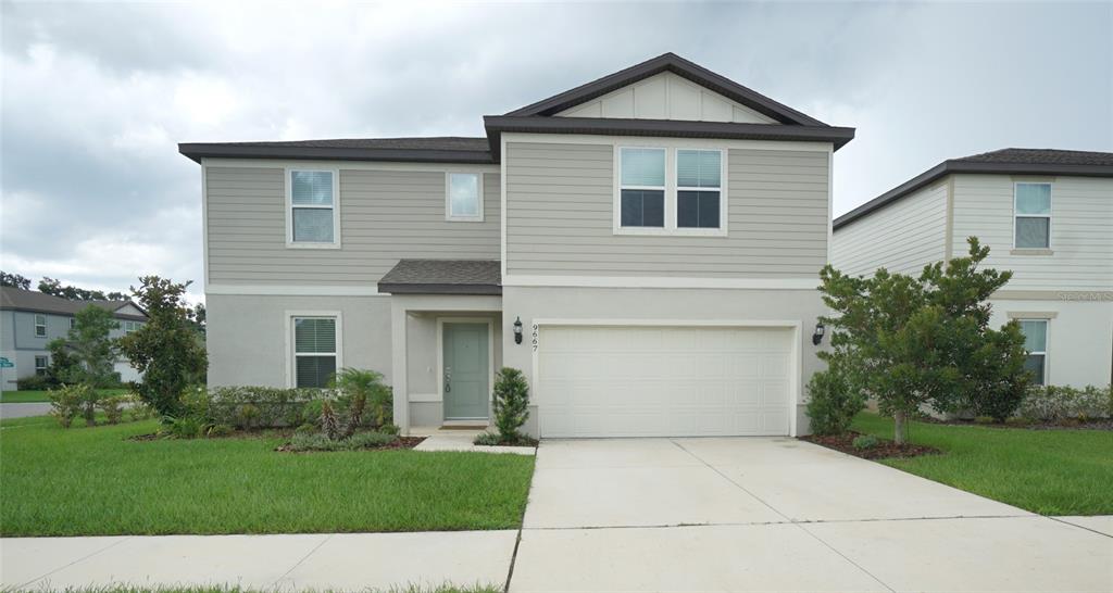 A modern kitchen features white cabinets, stainless steel appliances, and a large central island — 9667 SUMMERS CAY CIRCLE, THONOTOSASSA, FL