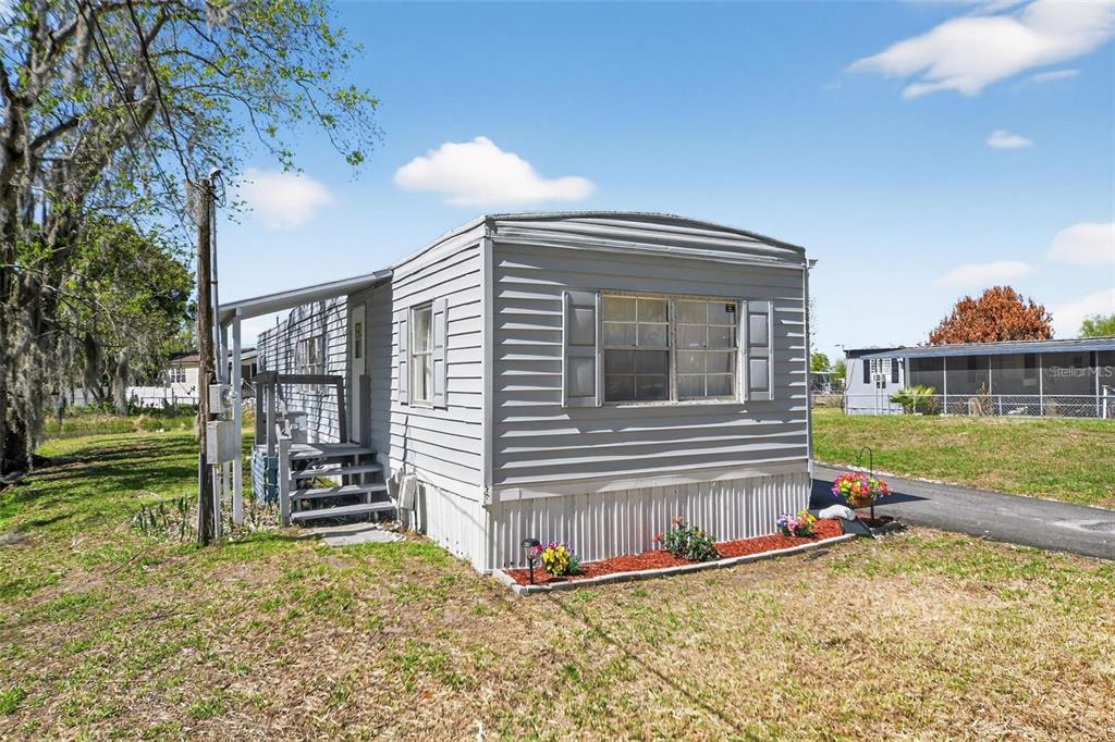 A gray mobile home with a small front porch and a landscaped flower bed — 2944 PALM CIRCLE, HAINES CITY, FL