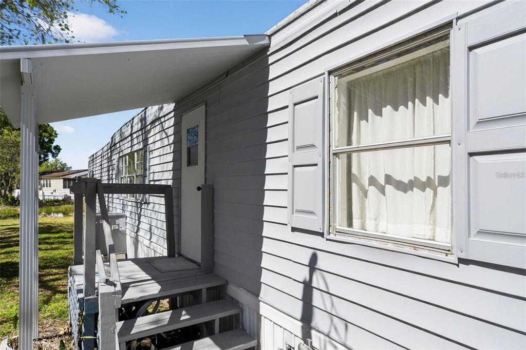 A gray mobile home exterior features a small wooden staircase leading to a white door — 2944 PALM CIRCLE, HAINES CITY, FL