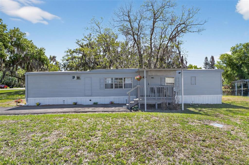 A single-story manufactured home with light gray siding, a front porch, and a paved driveway — 2944 PALM CIRCLE, HAINES CITY, FL