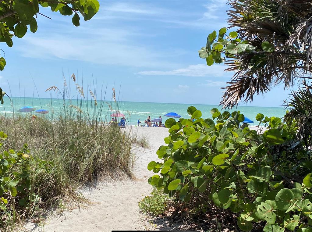 A sandy path leads through beach vegetation toward the ocean with people and umbrellas — 12550 RANCH AVENUE, PORT CHARLOTTE, FL