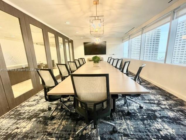 A modern conference room features a long wooden table, ergonomic chairs, and a large television — 777 Brickell Ave, Miami FL 33131, MIAMI, FL
