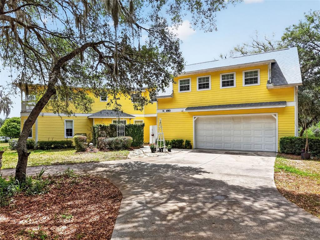 A two-story yellow house with a large garage and a concrete driveway — 493 MALAUKA LOOP, OCKLAWAHA, FL