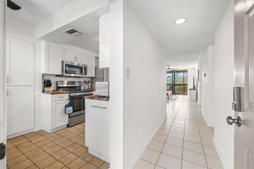 A view from an entryway looking into a kitchen with white cabinets and tiled floors — 1316 PASADENA AVENUE S UNIT 204, SOUTH PASADENA, FL