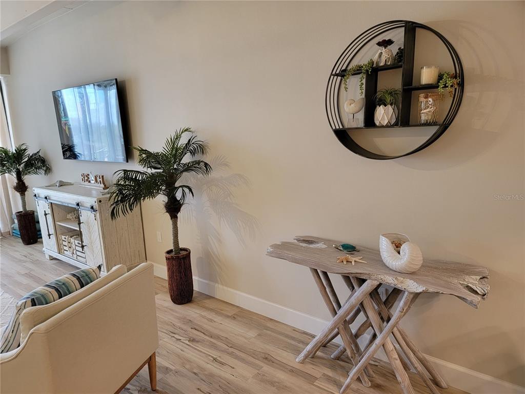 A living room features a driftwood console table, a circular wall shelf, and a TV console — 7650 BAYSHORE DRIVE UNIT 302, TREASURE ISLAND, FL