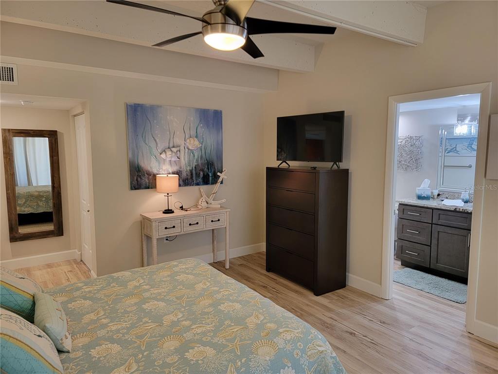 A bedroom features a bed, a dresser with a television, and an attached bathroom — 7650 BAYSHORE DRIVE UNIT 302, TREASURE ISLAND, FL