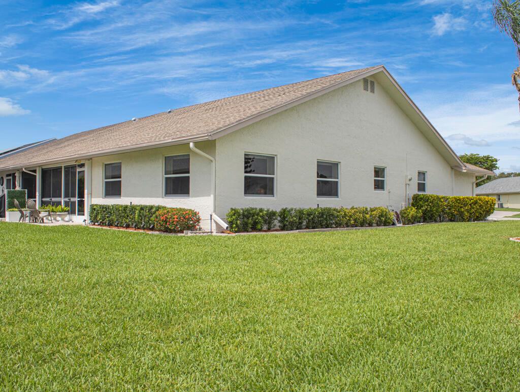 A side view of a single-story house with a beige stucco exterior and a grassy lawn — 3290 Belleville Road # 3290, West Palm Beach FL 33417, WEST PALM BEACH, FL