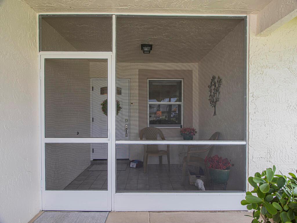 A screened-in front porch features a white door, tiled flooring, and two patio chairs — 3290 Belleville Road # 3290, West Palm Beach FL 33417, WEST PALM BEACH, FL
