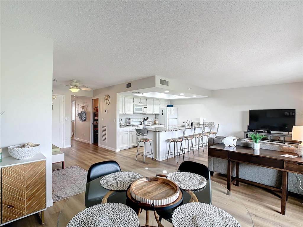 An open-concept living area features a kitchen with white cabinets, granite countertops, and bar seating — 19727 GULF BOULEVARD UNIT G1, INDIAN ROCKS BEACH, FL