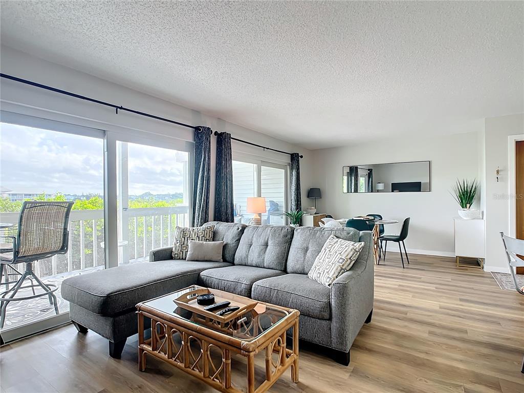 A living room features a grey sectional sofa, a rattan coffee table, and sliding glass doors — 19727 GULF BOULEVARD UNIT G1, INDIAN ROCKS BEACH, FL