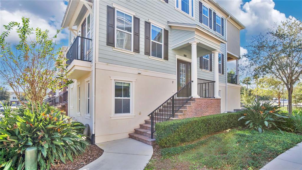 A multi-story building with light blue siding, a brick-accented front staircase, and a small balcony — 921 TARAMUNDI DRIVE, OVIEDO, FL